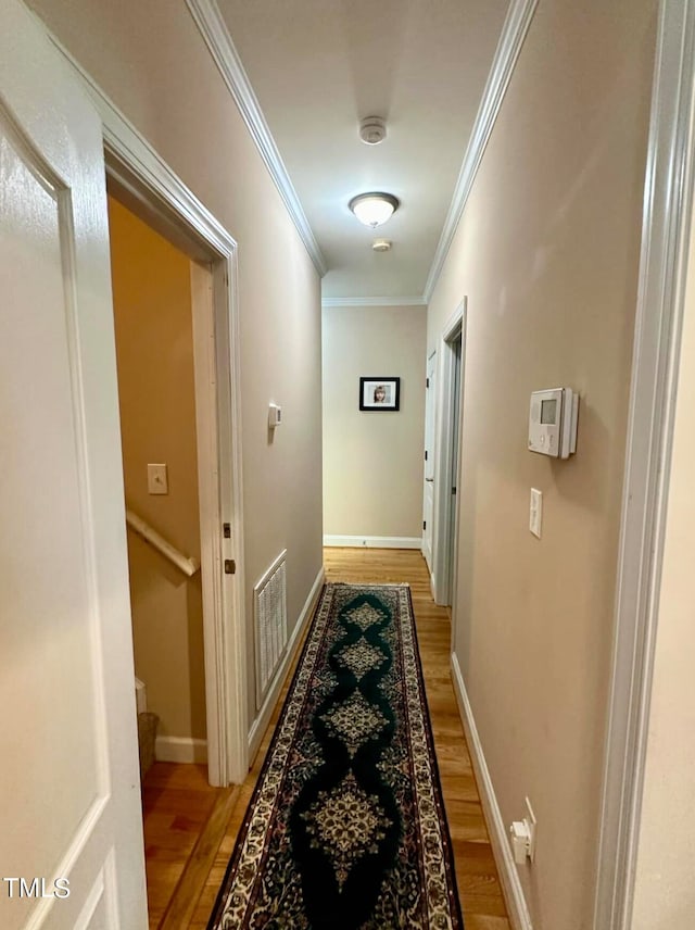 hallway with light hardwood / wood-style flooring and ornamental molding