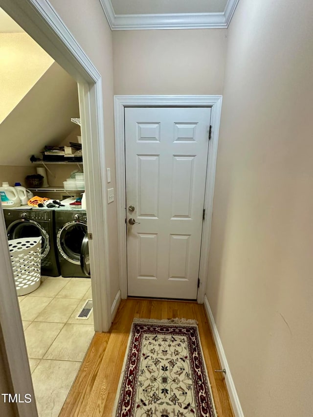 doorway to outside featuring light hardwood / wood-style flooring, ornamental molding, and washer and clothes dryer