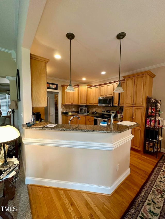 kitchen featuring hanging light fixtures, light hardwood / wood-style floors, kitchen peninsula, stainless steel appliances, and dark stone counters