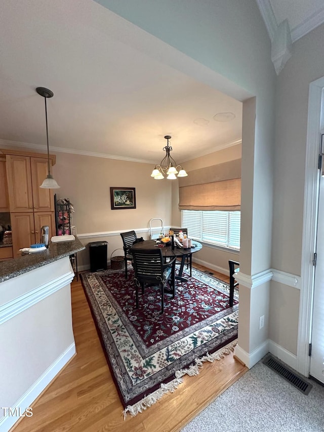 dining area with ornamental molding, a notable chandelier, and hardwood / wood-style floors