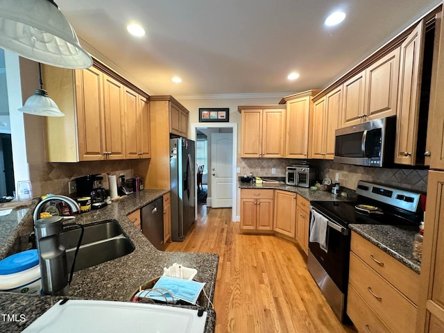 kitchen featuring appliances with stainless steel finishes, hanging light fixtures, crown molding, light hardwood / wood-style flooring, and sink