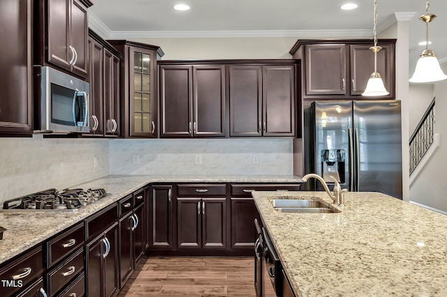 kitchen featuring wood-type flooring, sink, hanging light fixtures, stainless steel appliances, and ornamental molding