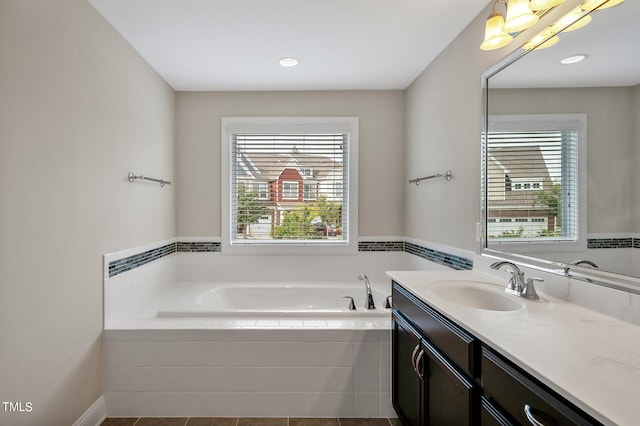 bathroom featuring tiled tub and vanity