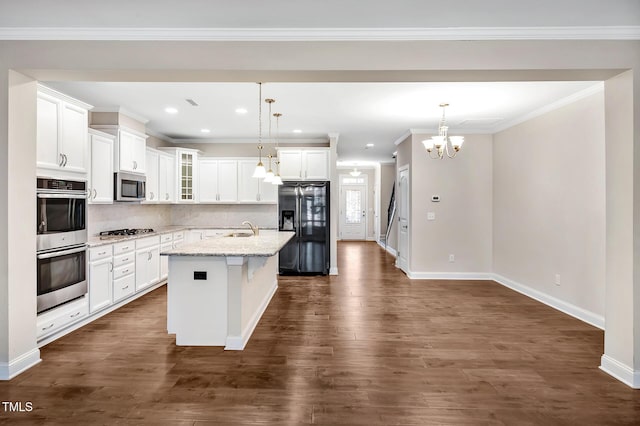 kitchen featuring an island with sink, appliances with stainless steel finishes, pendant lighting, and light stone counters