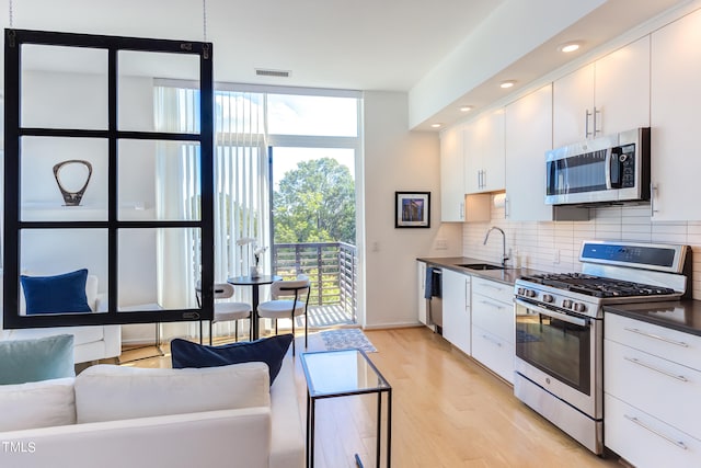 kitchen with decorative backsplash, stainless steel appliances, white cabinetry, and sink