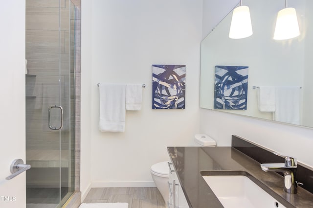 bathroom with hardwood / wood-style floors, a shower with door, vanity, and toilet