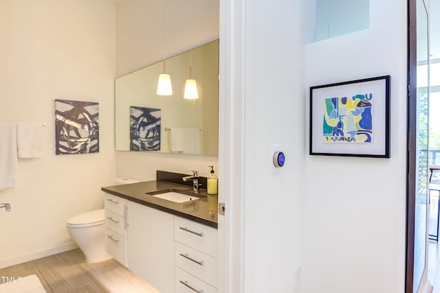 bathroom with wood-type flooring, vanity, and toilet