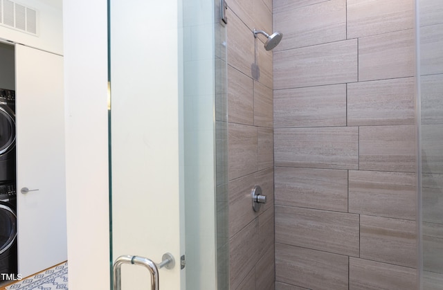 bathroom featuring stacked washer / drying machine and walk in shower