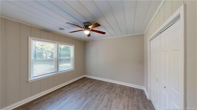 unfurnished bedroom with hardwood / wood-style floors, ornamental molding, a closet, and ceiling fan