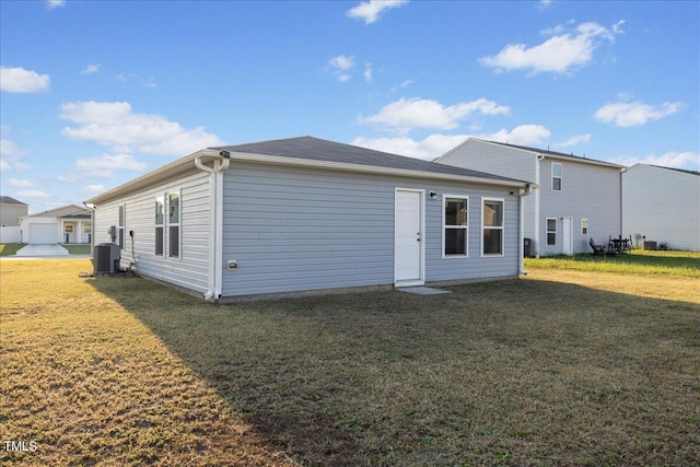 rear view of property with a garage, cooling unit, and a yard