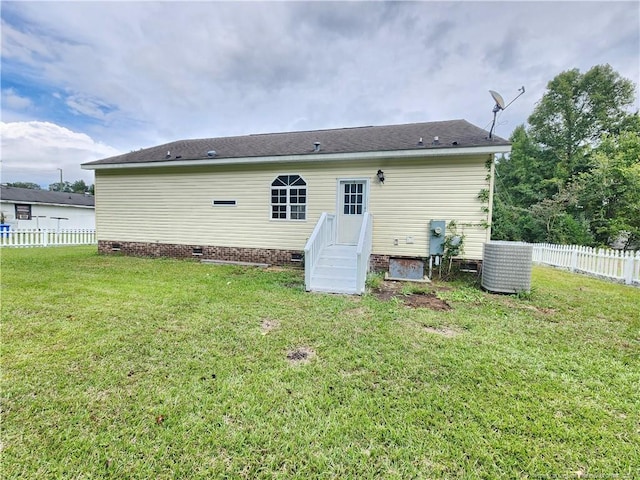 back of property featuring cooling unit and a lawn