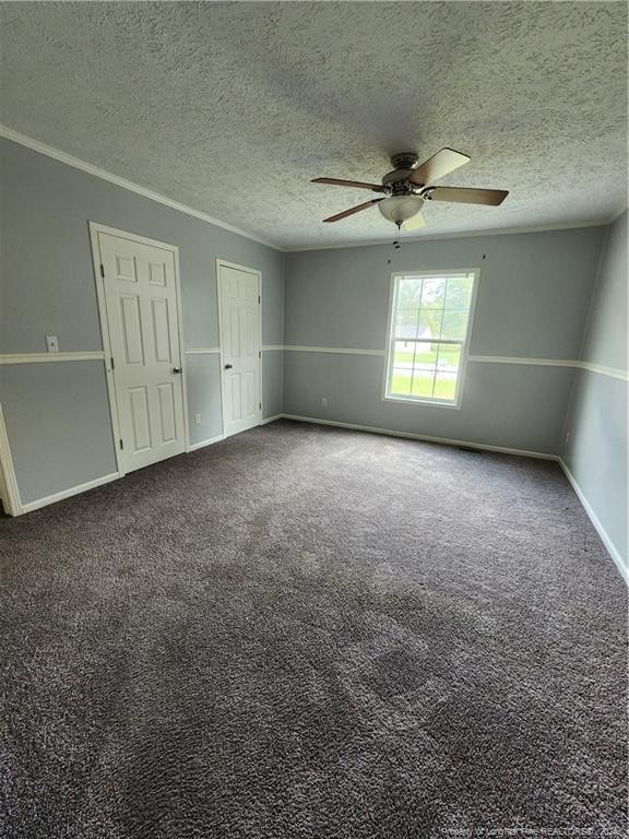 carpeted spare room with ceiling fan, ornamental molding, and a textured ceiling