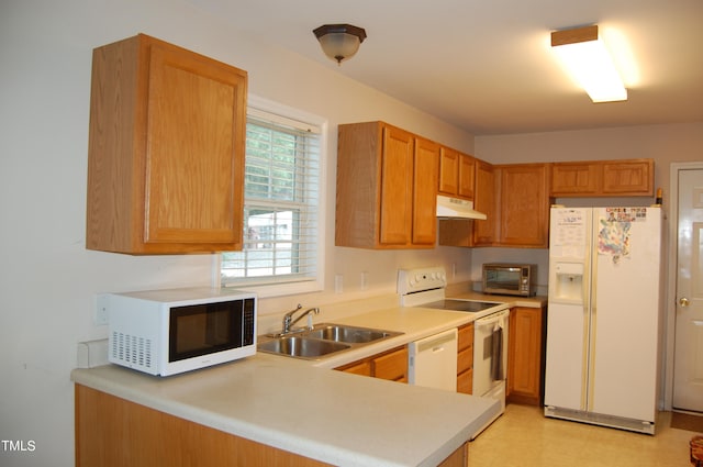 kitchen with white appliances, kitchen peninsula, and sink