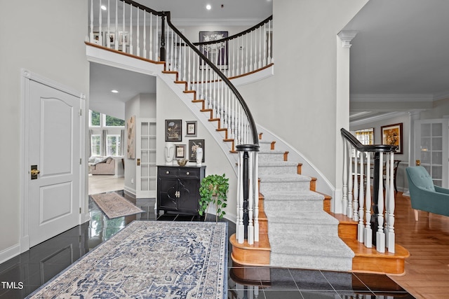 foyer with crown molding, stairway, baseboards, a towering ceiling, and granite finish floor