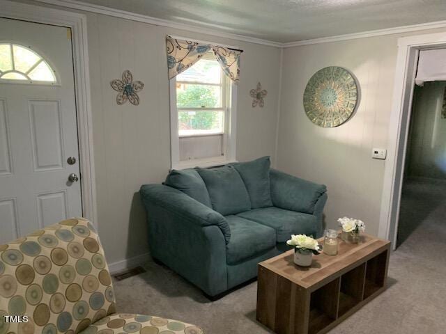living area with carpet floors, ornamental molding, visible vents, and baseboards