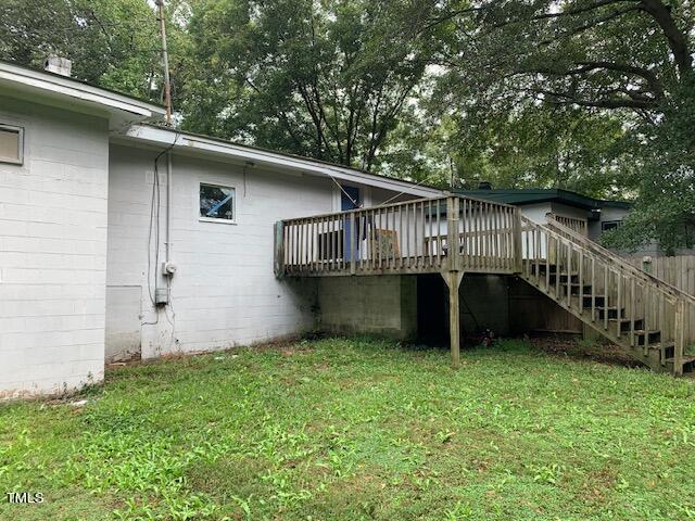 rear view of property with a lawn, a deck, and stairs