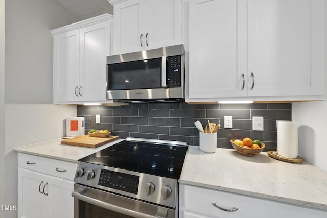 kitchen featuring stainless steel appliances, light stone countertops, decorative backsplash, and white cabinets