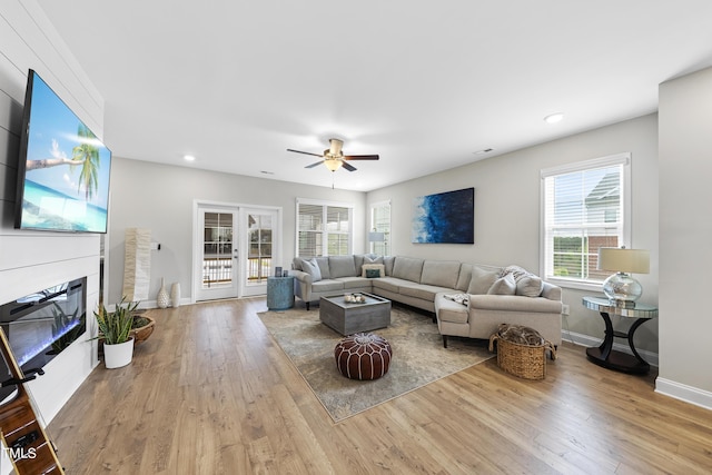 living room with french doors, ceiling fan, and light wood-type flooring