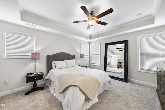 bedroom with ornamental molding, light colored carpet, and a tray ceiling