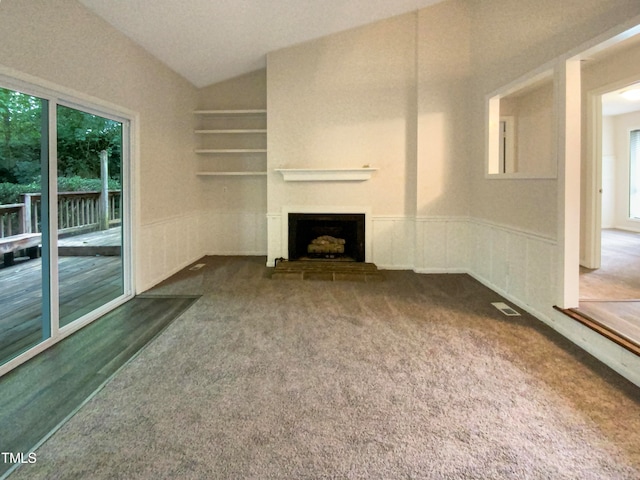 unfurnished living room featuring carpet flooring, vaulted ceiling, and a healthy amount of sunlight