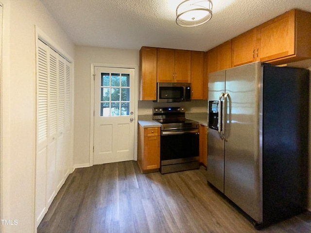 kitchen featuring a textured ceiling, appliances with stainless steel finishes, and dark hardwood / wood-style flooring