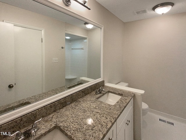 bathroom featuring a textured ceiling, walk in shower, vanity, and toilet