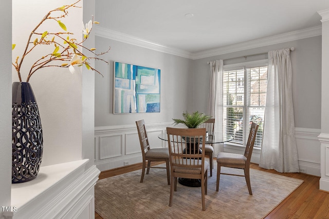 dining space with light hardwood / wood-style flooring, crown molding, and decorative columns