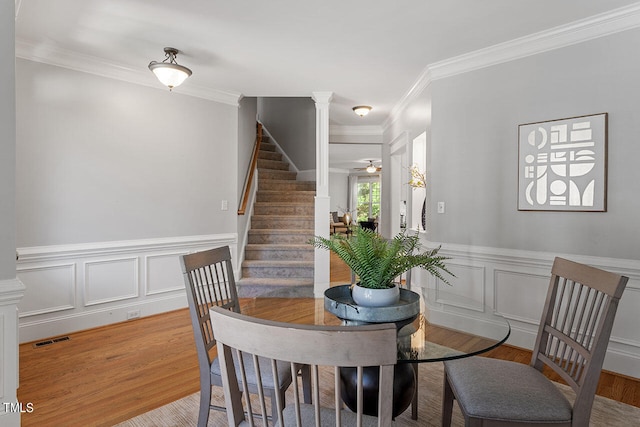 dining area with ornamental molding, decorative columns, ceiling fan, and light hardwood / wood-style floors