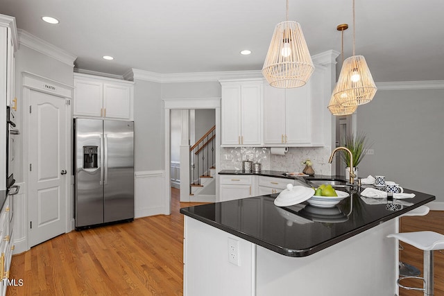 kitchen featuring white cabinets, hanging light fixtures, sink, light hardwood / wood-style flooring, and stainless steel appliances