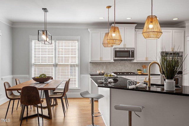 kitchen with stainless steel appliances, pendant lighting, light hardwood / wood-style floors, and white cabinetry