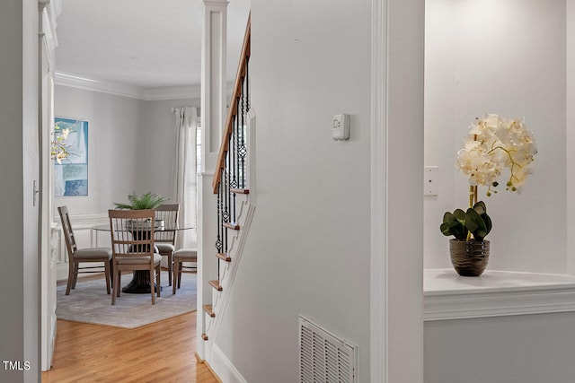 hallway with crown molding and light wood-type flooring