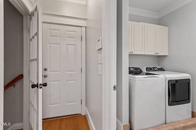 laundry area with crown molding, separate washer and dryer, light hardwood / wood-style floors, and cabinets