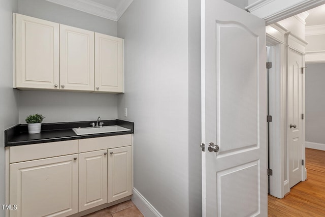 bar with crown molding, white cabinetry, sink, and light hardwood / wood-style flooring