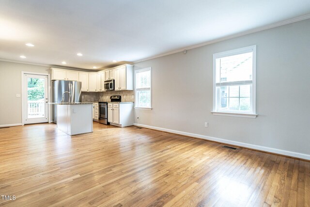 kitchen featuring white cabinets, a center island, stainless steel appliances, and a wealth of natural light