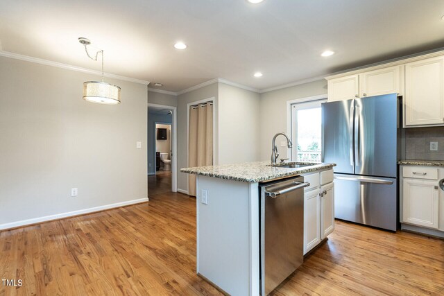 kitchen featuring light wood-type flooring, stainless steel appliances, a center island with sink, and sink