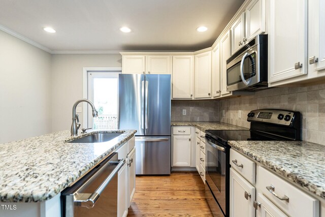 kitchen featuring white cabinets, sink, light wood-type flooring, ornamental molding, and appliances with stainless steel finishes