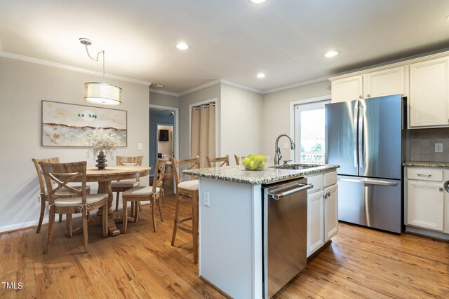 kitchen featuring sink, an island with sink, stainless steel appliances, and light wood-type flooring