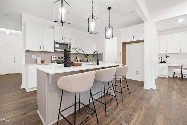 kitchen with white cabinets, stainless steel appliances, a center island with sink, and sink