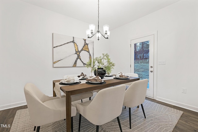 dining space with dark wood-type flooring and an inviting chandelier