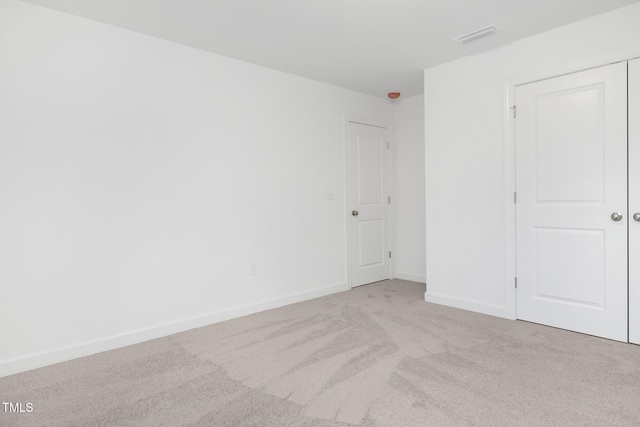 unfurnished bedroom with light colored carpet and a closet