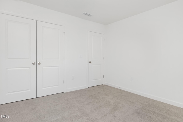 unfurnished bedroom featuring light carpet and a closet