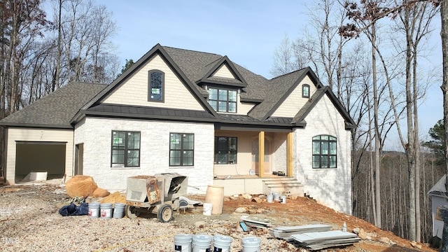 view of front facade featuring roof with shingles, a porch, an attached garage, a standing seam roof, and metal roof