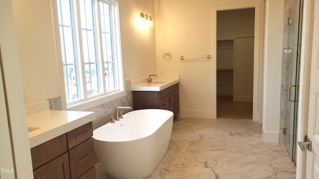 full bathroom featuring marble finish floor, two vanities, a sink, a shower stall, and a freestanding tub