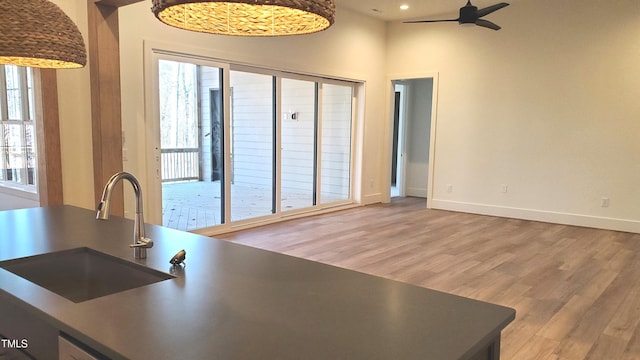 interior space featuring a wealth of natural light, baseboards, a sink, and light wood finished floors