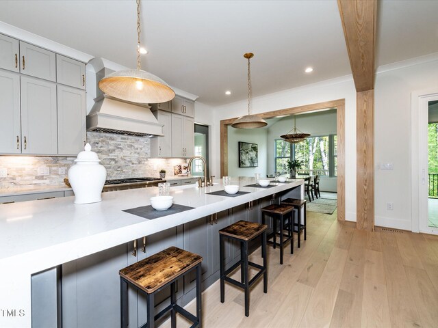 144 W Beech Slope Ct, Chapel Hill, NC 27517 - kitchen with light countertops, premium range hood, light wood-type flooring, backsplash, and gray cabinetry
