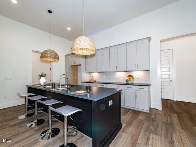 144 W Beech Slope Ct, Chapel Hill, NC 27517 - kitchen with a breakfast bar area, dark countertops, tasteful backsplash, wood finished floors, and a sink