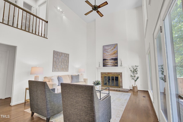 living room with ceiling fan, a fireplace, dark hardwood / wood-style floors, and high vaulted ceiling