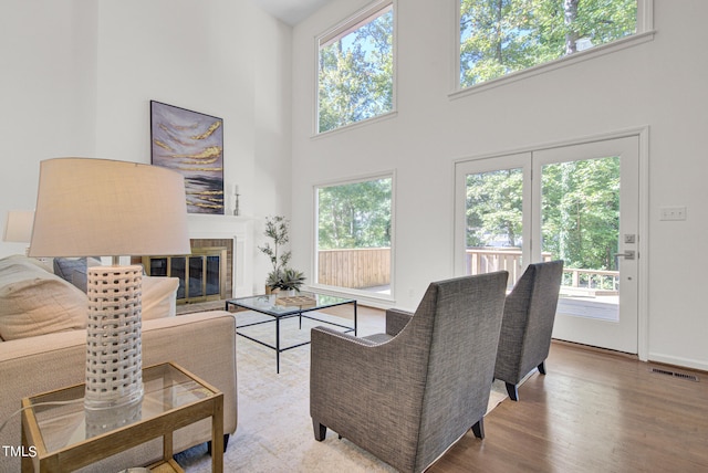 living room featuring a brick fireplace, a high ceiling, and hardwood / wood-style flooring