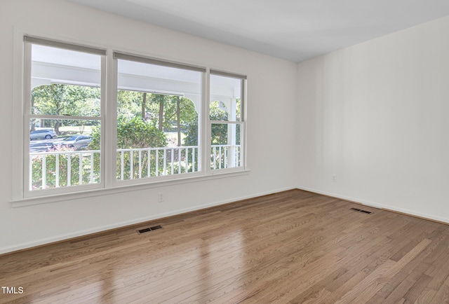 empty room with plenty of natural light and hardwood / wood-style floors