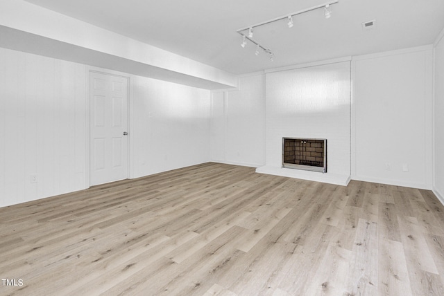 unfurnished living room with track lighting, a fireplace, and light hardwood / wood-style floors